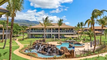 A resort with a pool area, palm trees, and a building with a balcony.