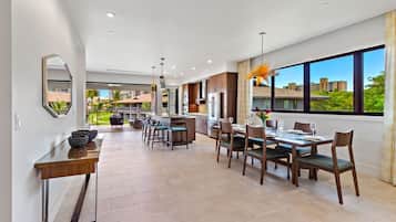 A modern kitchen with a dining area, large windows, and a view of the surrounding buildings.