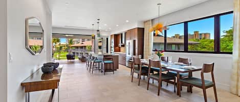 A modern kitchen with a dining area, large windows, and a view of the surrounding buildings.