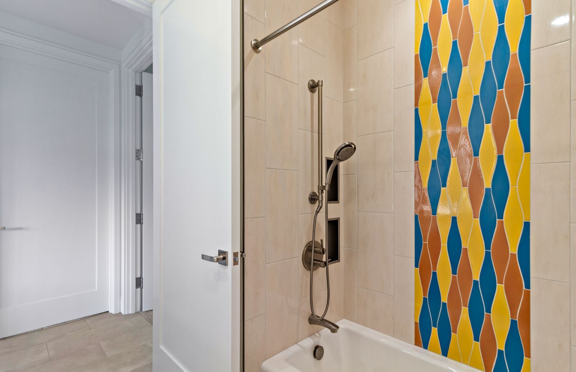 A bathroom with a shower, a door, and a tiled wall.