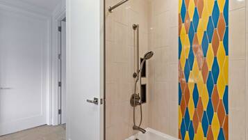 A bathroom with a shower, a door, and a tiled wall.
