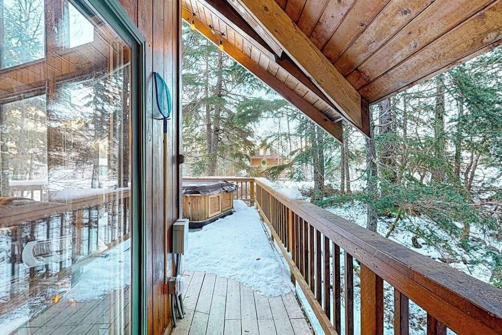 A wooden deck with a glass door leading to a snowy forest.