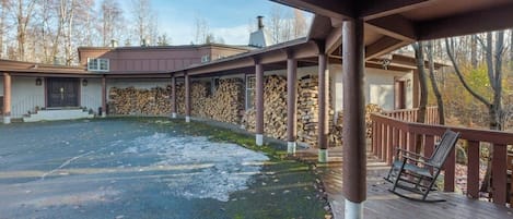 Un espacio al aire libre cubierto con una terraza de madera, un muro de piedra y una pila de leña.