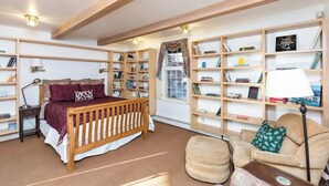 Um quarto com uma cama, um sofá e várias estantes repletas de livros.