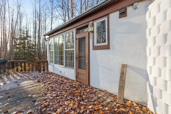 A cabin with a wooden deck, a door, and windows.