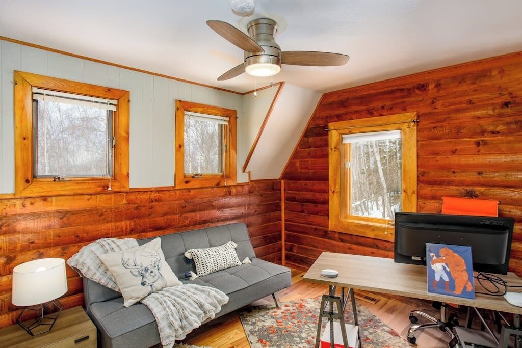 L’intérieur d’un chalet confortable, avec un canapé, un bureau et un téléviseur.