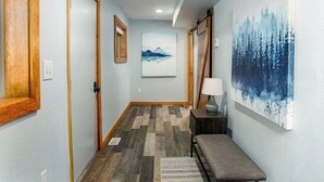 Un corridoio con porte in legno, una panca, una lampada e un quadro appeso al muro.