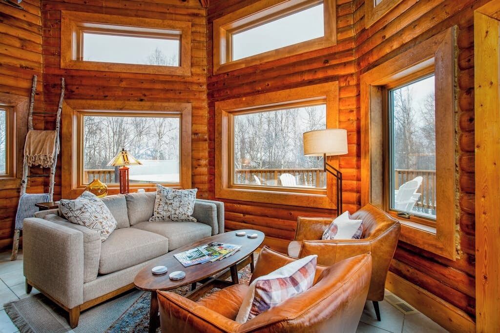A log cabin interior with a sofa, armchair, and a coffee table.