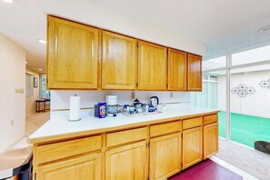 A kitchen with wooden cabinets, a white countertop, and various appliances. - Anchorage Flat Between Bootlegger Cove & Downtown (Anchorage)