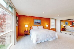 A bedroom with a large bed, two bedside tables, a window, and a mirror. - Anchorage Flat Between Bootlegger Cove & Downtown (Anchorage)