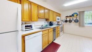Una cocina con gabinetes de madera, microondas, lavavajillas y estufa.