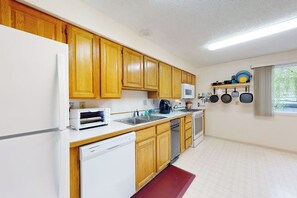 A kitchen with wooden cabinets, a microwave, a dishwasher, and a stove. - Anchorage Flat Between Bootlegger Cove & Downtown (Anchorage)