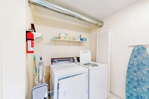 A laundry room with a washing machine, dryer, and ironing board. - Anchorage Flat Between Bootlegger Cove & Downtown (Anchorage)