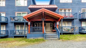 A building with a red-roofed entrance, multiple balconies, and a gravel driveway. - Budget-friendly Studio Near Alyeska Lifts (Girdwood)