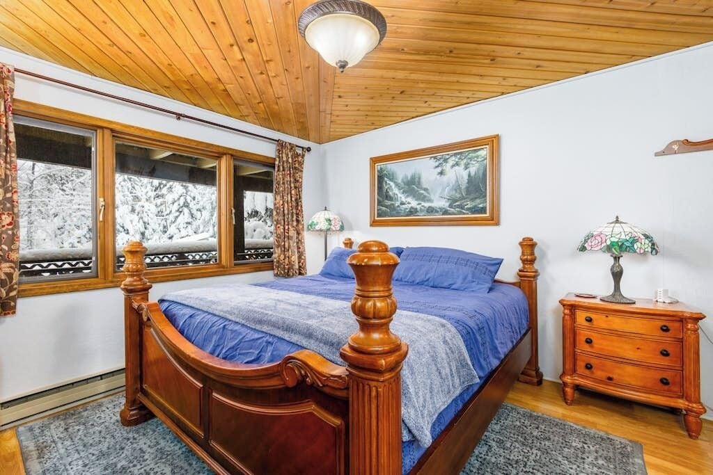 A bedroom with a wooden bed, a nightstand, a lamp, and a painting on the wall.