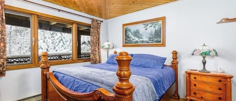 A bedroom with a wooden bed, a nightstand, a lamp, and a painting on the wall.