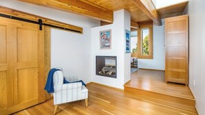 A room with wooden flooring, a white sofa, a fireplace, and a wooden door. - Award-winning Anchorage Kitchen w/ Cook Inlet Views (Anchorage)
