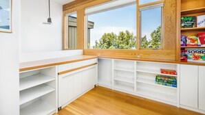 A kitchen with white cabinetry, a wooden countertop, and a window with a view of trees. - Award-winning Anchorage Kitchen w/ Cook Inlet Views (Anchorage)