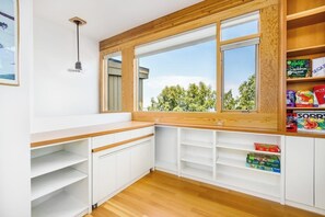 A kitchen with white cabinetry, a wooden countertop, and a window with a view of trees. - Award-winning Anchorage Kitchen w/ Cook Inlet Views (Anchorage)