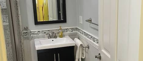 Un baño con un lavamanos blanco, muebles negros, un espejo y un perchero para toallas.