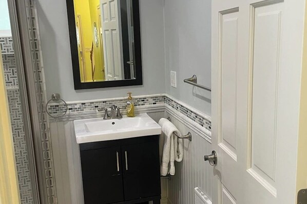 A bathroom with a white sink, black cabinets, a mirror, and a towel rack.