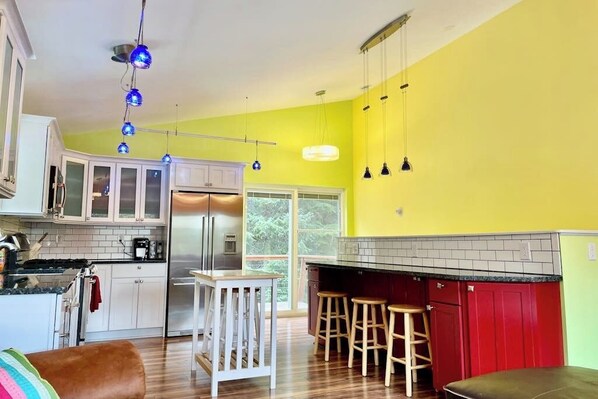 A kitchen with white cabinets, a red countertop, and a bar area with stools.