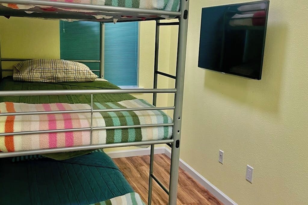 A bunk bed with a television mounted on the wall above it.