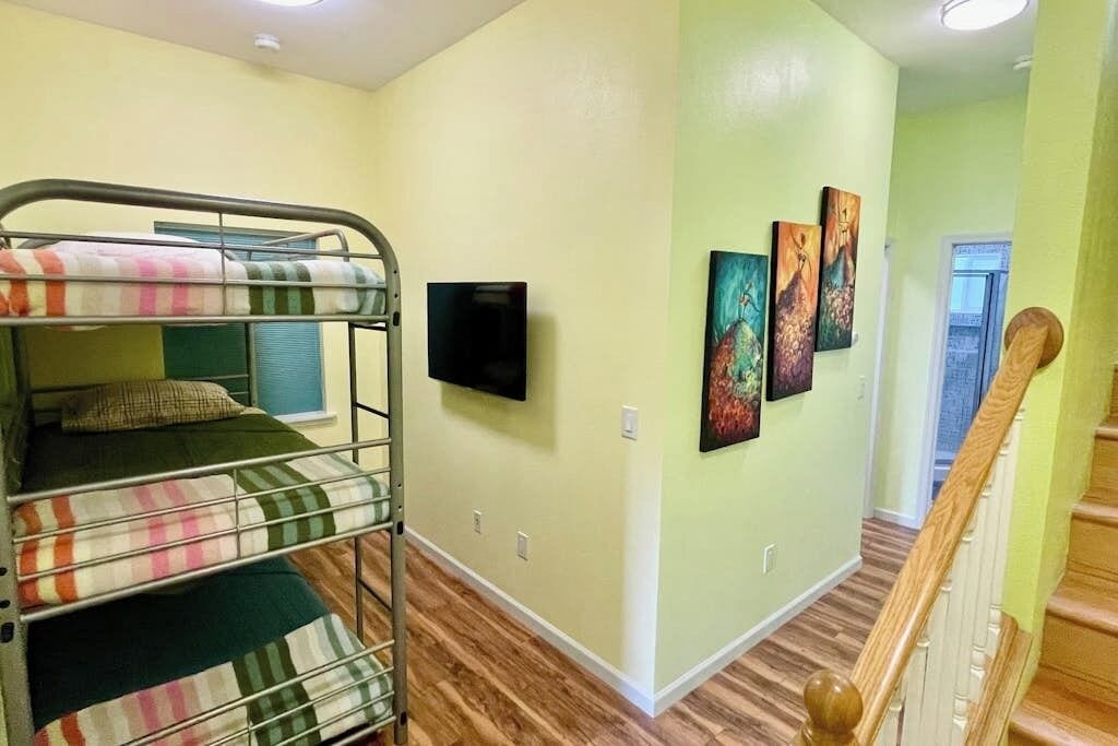 A room with bunk beds, a flat-screen TV, and artwork on the wall.