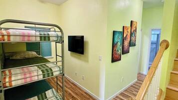 A room with bunk beds, a flat-screen TV, and artwork on the wall.
