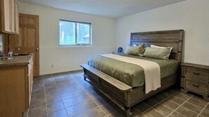 Quarto com cama, mesa de cabeceira, cômoda e janela.