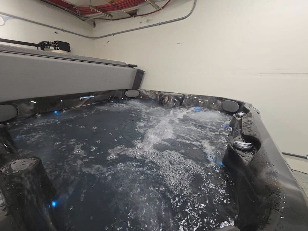 A hot tub with water, surrounded by a dark-colored tub.