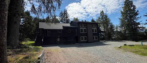 Un edificio de dos pisos con camino de grava, rodeado de árboles.