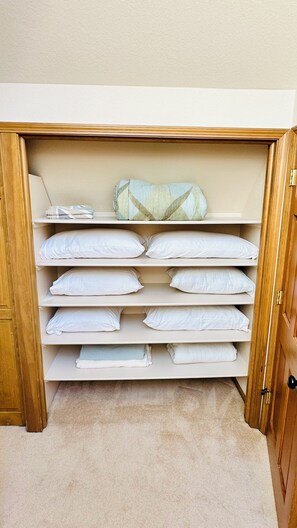 Ein Schrank mit mehreren Regalen und Ablagefläche für Kleidung, der gefaltete Kleidung und eine Decke beherbergt.