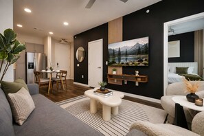 A modern living room with a dining area, a large flat-screen TV mounted on the wall, and a cozy seating arrangement. - Sleek Haven Suite, Pool, Gym, Parking, Downtown San Antonio (San Antonio)