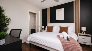 A hotel room with a bed, bedside tables, a desk, a chair, and a ceiling fan. - Sleek Haven Suite  | Pool • Gym • Parking | Downtown San Antonio (San Antonio)