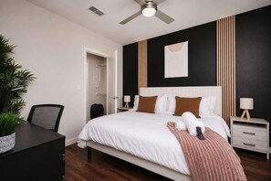 A hotel room with a bed, bedside tables, a desk, a chair, and a ceiling fan. - Sleek Haven Suite  | Pool • Gym • Parking | Downtown San Antonio (San Antonio)