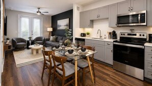 A modern kitchen with grey cabinets, a stainless steel microwave, and a black oven. - Sleek Haven Suite  | Pool • Gym • Parking | Downtown San Antonio (San Antonio)