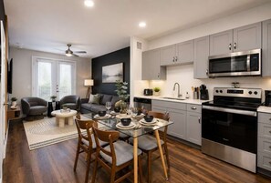 A modern kitchen with grey cabinets, a stainless steel microwave, and a black oven. - Sleek Haven Suite  | Pool • Gym • Parking | Downtown San Antonio (San Antonio)