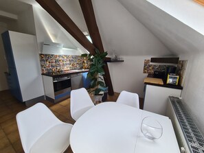 A compact kitchen with a tiled backsplash, a dining area with white chairs, and a small table. - Villa in Adelsheim - Historischer Charme im Herzen von Adelsheim (Adelsheim)