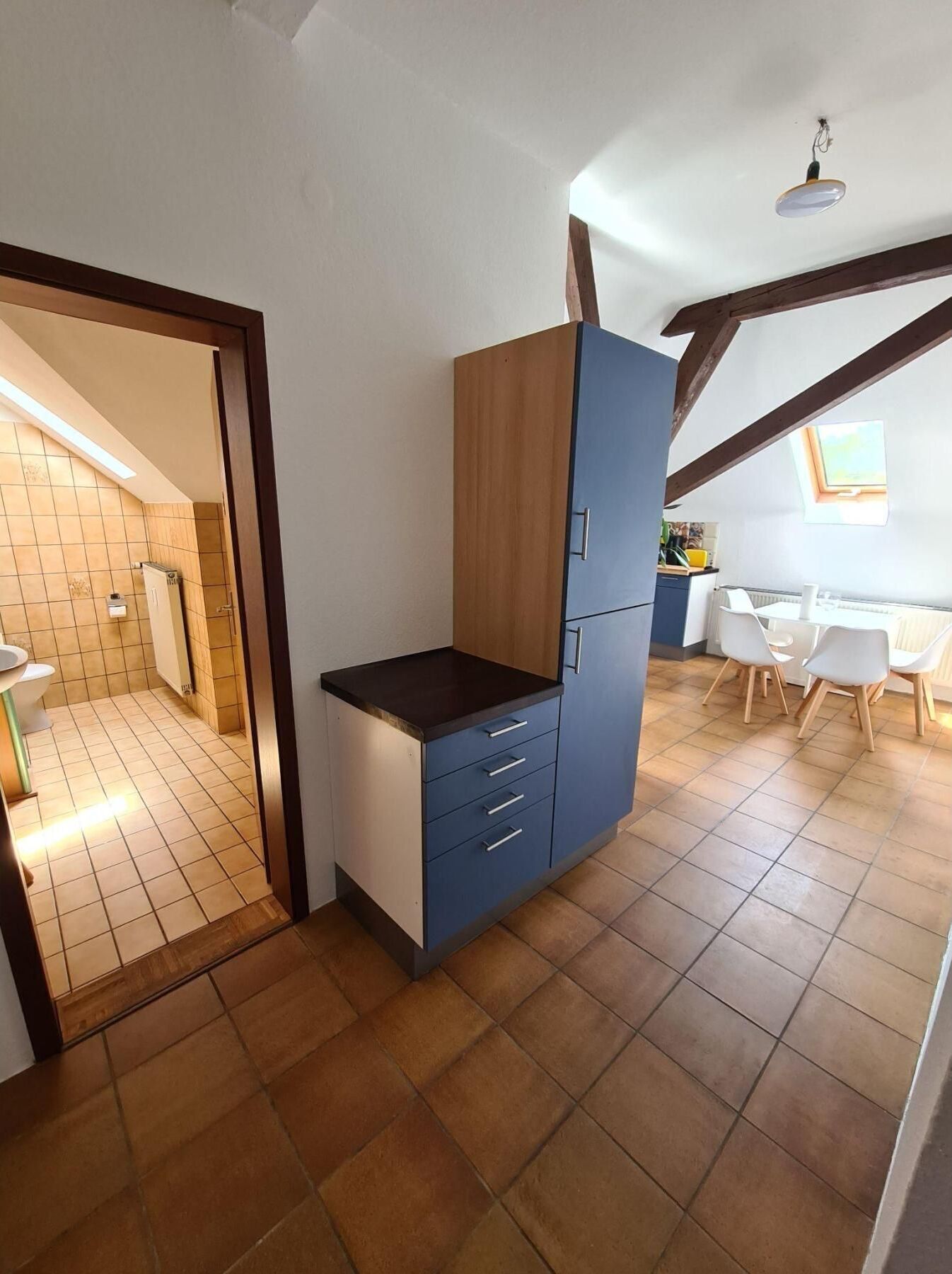 Una cucina compatta con un pensile integrato e un piccolo angolo ristoro con tavolo e sedie.