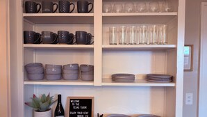 Una estantería con tazas, vasos y platos diversos.
