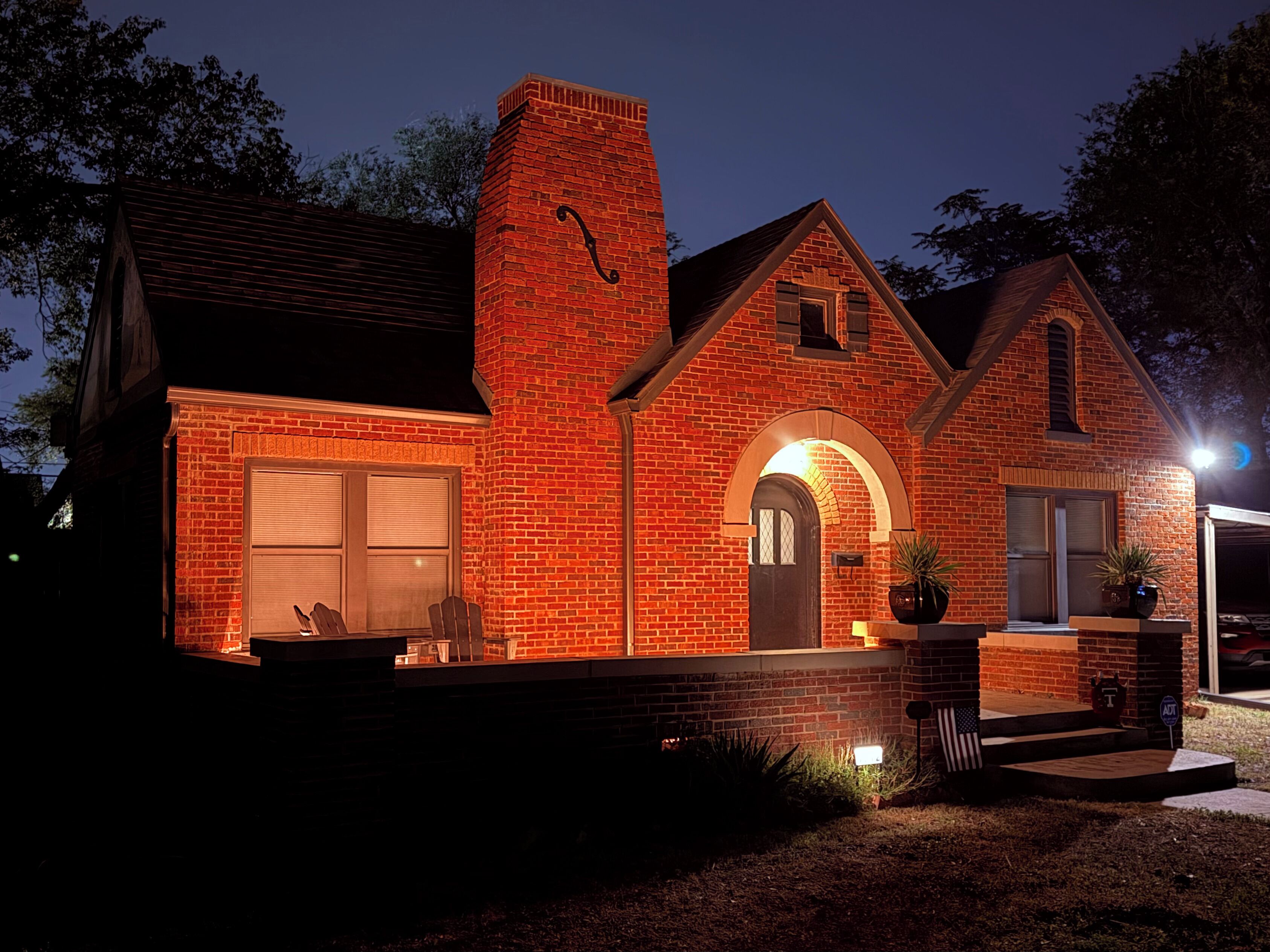 A brick house with a large garage, a front porch, and a chimney.