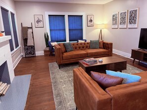 Ein Wohnzimmer mit braunem Sofa, einem Couchtisch, einem TV-Schrank und einem Kamin.