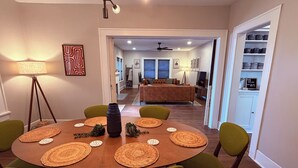 Un comedor con una mesa redonda, sillas verdes y posavasos tejidos.