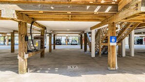 Un área de estacionamiento techada con vigas de madera, piso de concreto y un letrero de estacionamiento azul.