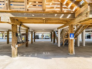 Ein überdachter Parkbereich mit Holzbalken, Betonboden und einem blauen Parkschild.