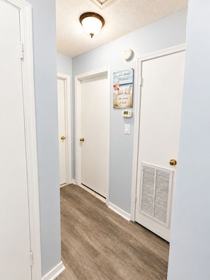 A hallway with two white doors, a thermostat, and a vent on the wall. - Gulf View 17: Steps to Beach, Walk to The Hangout, Pool, Pet-Friendly (Gulf Shores)