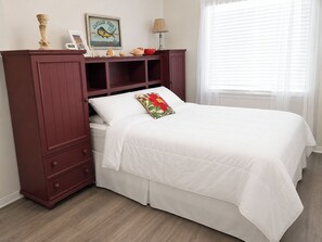 A bedroom with a bed, a nightstand, a dresser, a lamp, and a window with blinds. - Gulf View 17: Steps to Beach, Walk to The Hangout, Pool, Pet-Friendly (Gulf Shores)