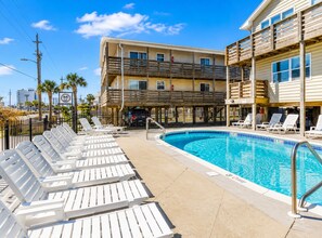 A swimming pool with lounge chairs and a building with balconies. - Gulf View 17: Steps to Beach, Walk to The Hangout, Pool, Pet-Friendly (Gulf Shores)