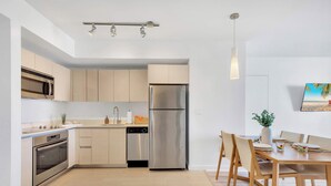 Eine moderne Küche mit Edelstahlgeräten, einem Essbereich mit Holztisch und Stühlen sowie einer Pendelleuchte.